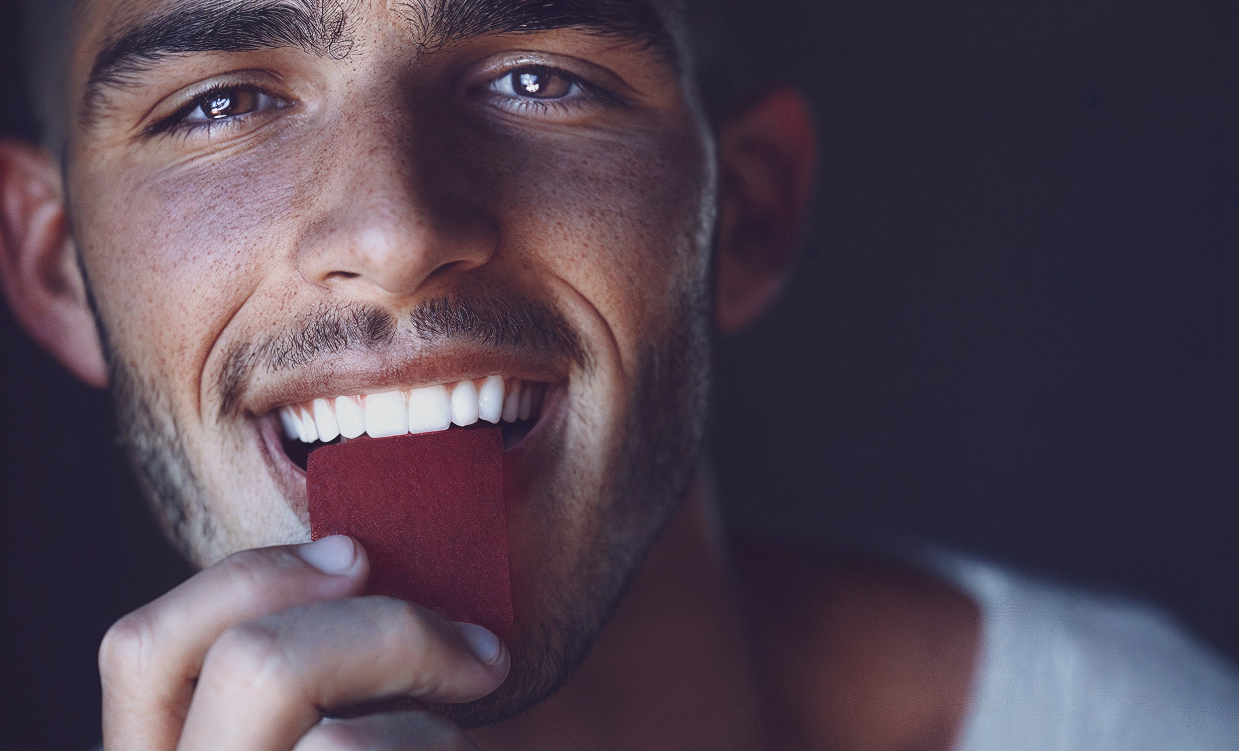 Close-up of a man smiling while placing a wellness strip in his mouth, showing how the product is used for easy consumption.