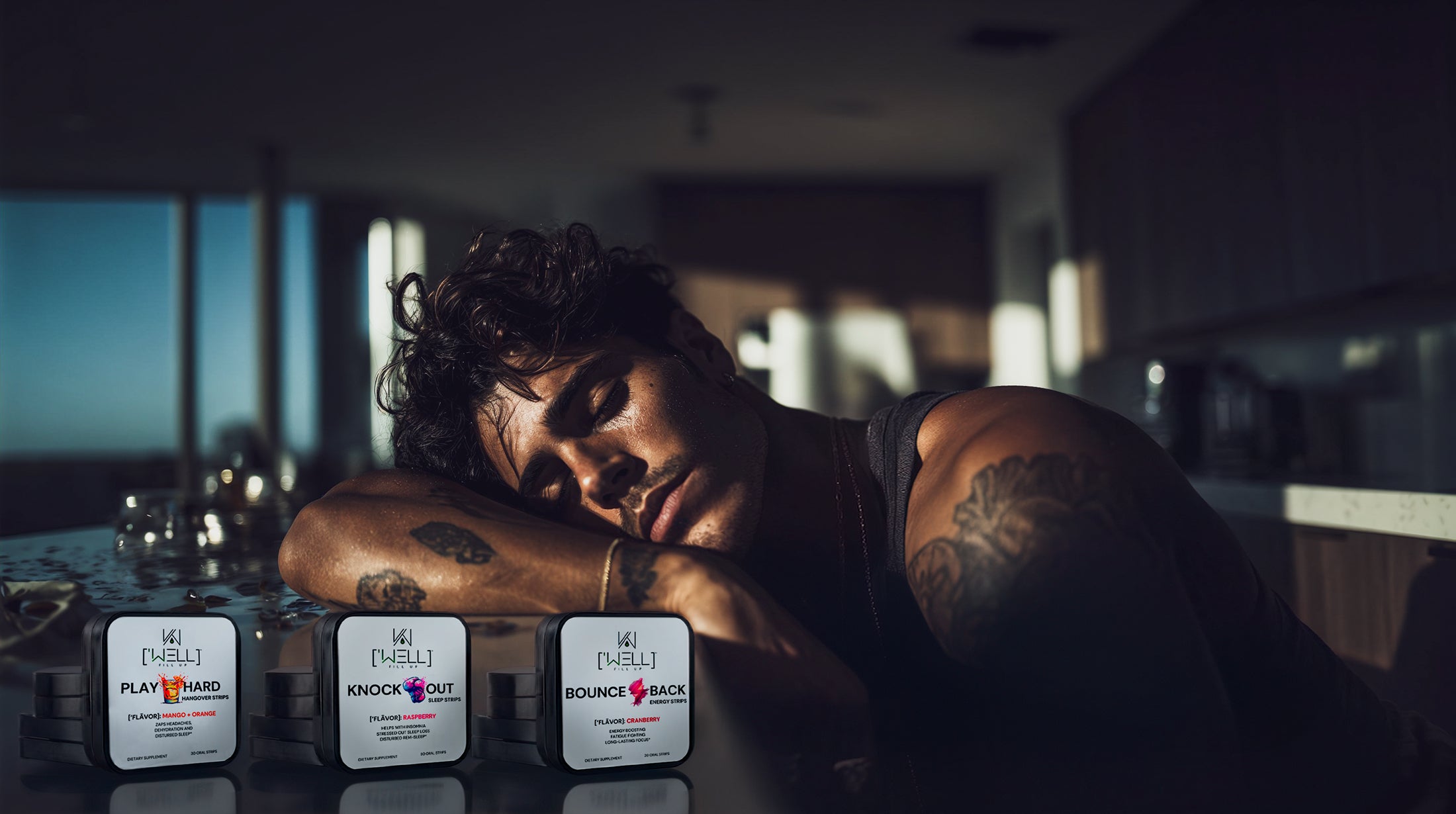 Man with tattoos leaning on a table with product boxes in a dimly lit room
